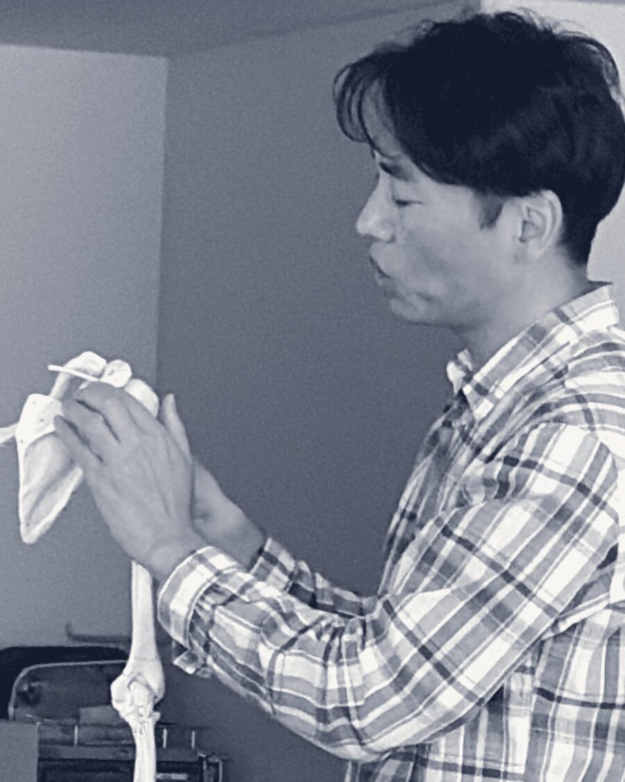 骨の模型を手に持って説明している様子